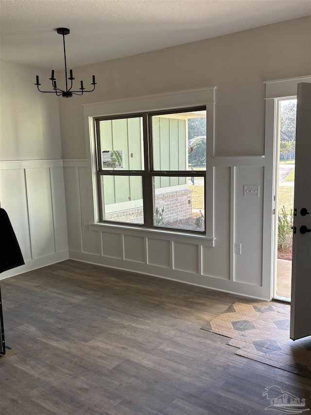 unfurnished dining area featuring a healthy amount of sunlight, a decorative wall, and dark wood finished floors