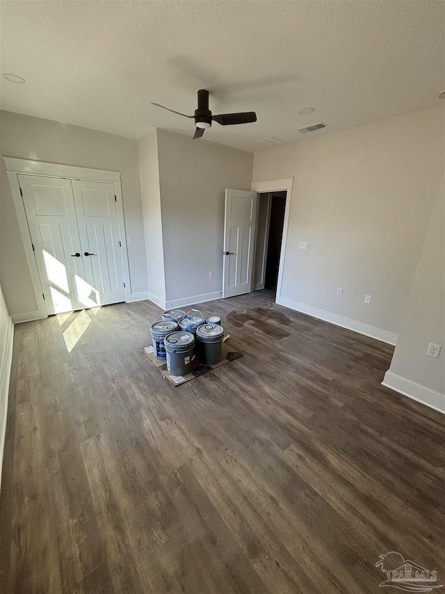 unfurnished bedroom with dark wood-style floors, visible vents, ceiling fan, a textured ceiling, and baseboards