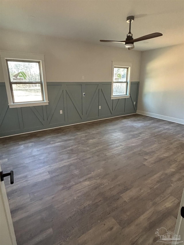 unfurnished room with ceiling fan, wainscoting, and dark wood finished floors