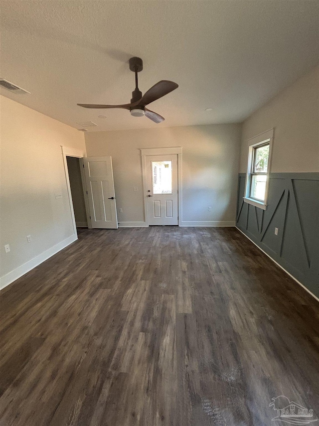 unfurnished room featuring baseboards, visible vents, a ceiling fan, dark wood finished floors, and a textured ceiling