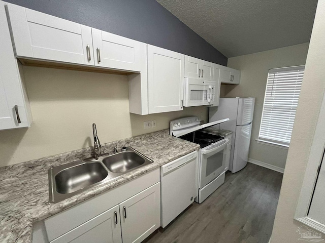 kitchen featuring white appliances, lofted ceiling, light countertops, white cabinetry, and a sink