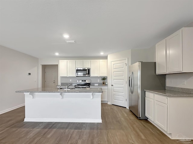 kitchen featuring a kitchen breakfast bar, appliances with stainless steel finishes, and white cabinets