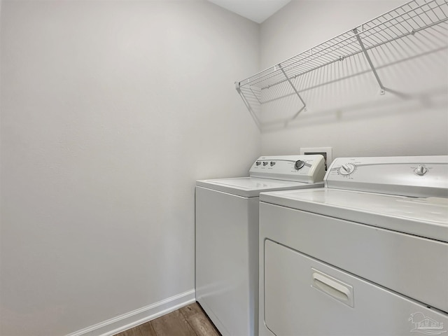 laundry area with wood finished floors, baseboards, washing machine and dryer, and laundry area