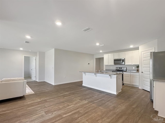 kitchen with dark wood-type flooring, open floor plan, a breakfast bar area, stainless steel appliances, and white cabinetry