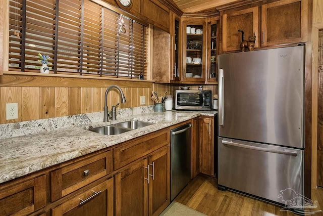 kitchen featuring light stone countertops, sink, light hardwood / wood-style flooring, and appliances with stainless steel finishes