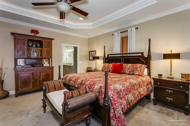 bedroom featuring a tray ceiling, ensuite bathroom, ceiling fan, and ornamental molding