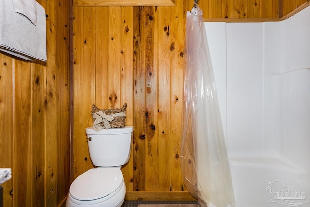 bathroom featuring wood walls and toilet