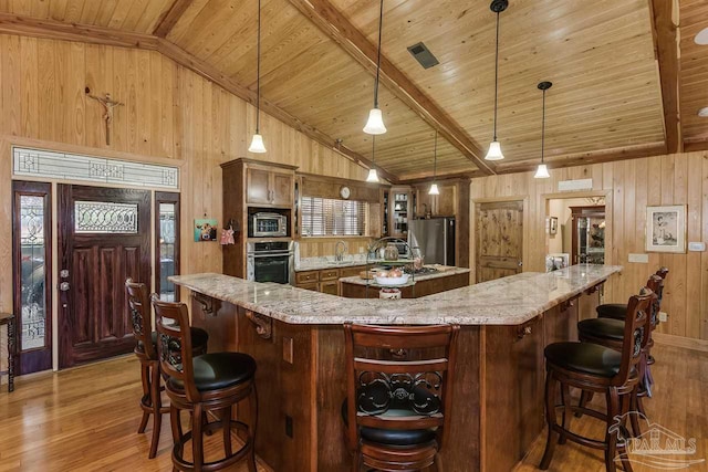 kitchen featuring vaulted ceiling with beams, wood ceiling, hanging light fixtures, and stainless steel appliances