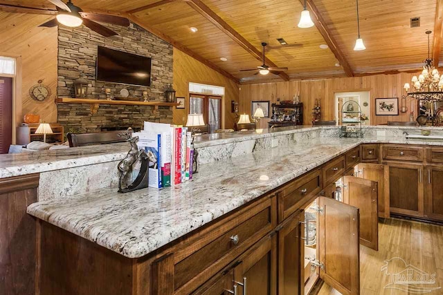 kitchen with hanging light fixtures, wooden ceiling, light hardwood / wood-style flooring, lofted ceiling with beams, and wood walls