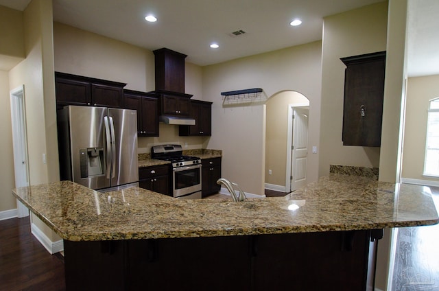 4777 Belvedere Cir, Pace, FL 32571 - kitchen with appliances with stainless steel finishes, under cabinet range hood, arched walkways, light stone countertops, and baseboards