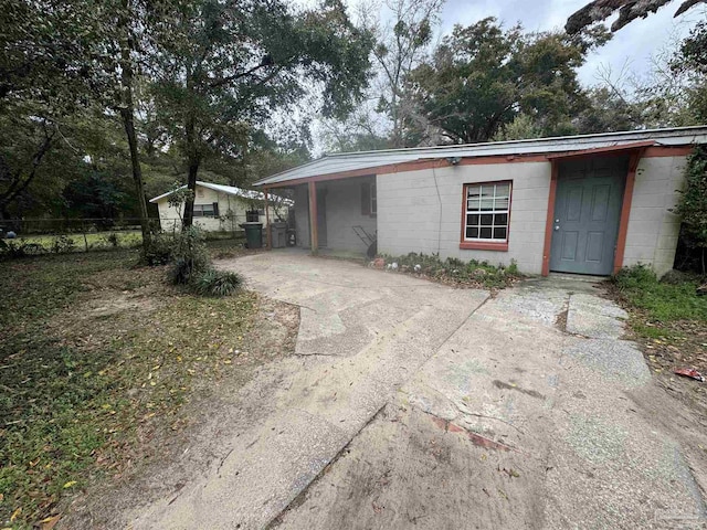 view of front of property featuring fence, concrete block siding, and concrete driveway