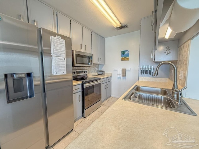 1448 Tina Dr Unit 213, Navarre Beach, FL 32566 - kitchen with stainless steel appliances, a sink, decorative backsplash, light tile patterned flooring, and light countertops