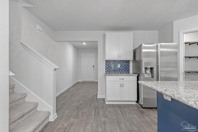 5457 Merlin Way, Milton, FL 32583 - kitchen featuring stainless steel fridge, light wood finished floors, white cabinets, and light stone countertops