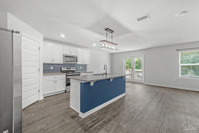 5457 Merlin Way, Milton, FL 32583 - kitchen with appliances with stainless steel finishes, white cabinets, light stone countertops, dark wood-type flooring, and recessed lighting