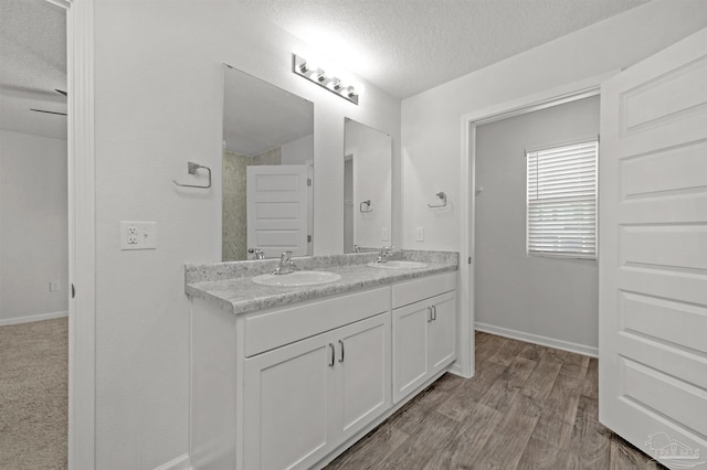 5457 Merlin Way, Milton, FL 32583 - bathroom with double vanity, a textured ceiling, baseboards, and wood finished floors