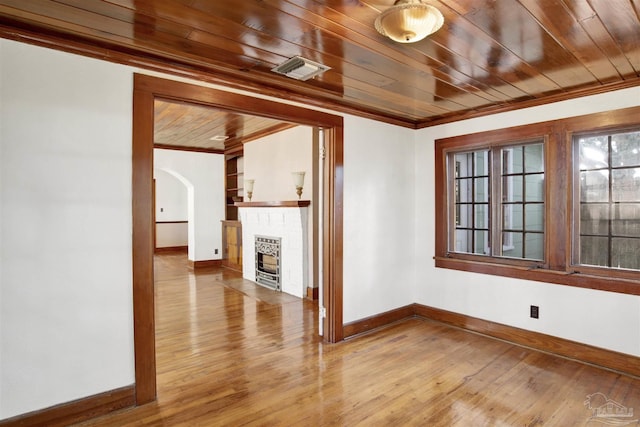 unfurnished room with a fireplace, wood ceiling, and crown molding