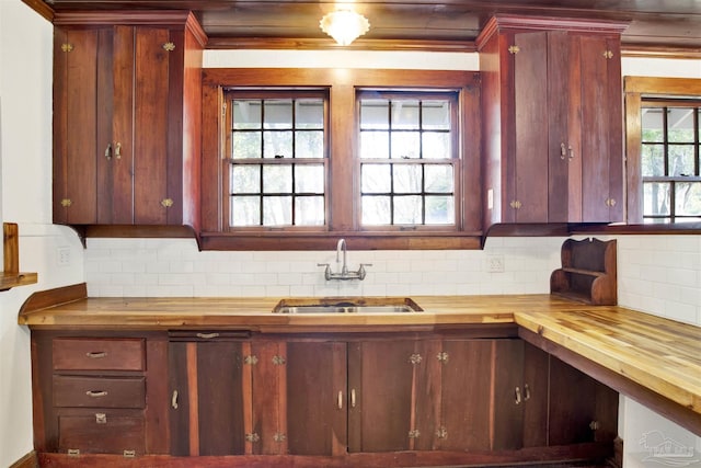 kitchen featuring tasteful backsplash, butcher block counters, and a sink