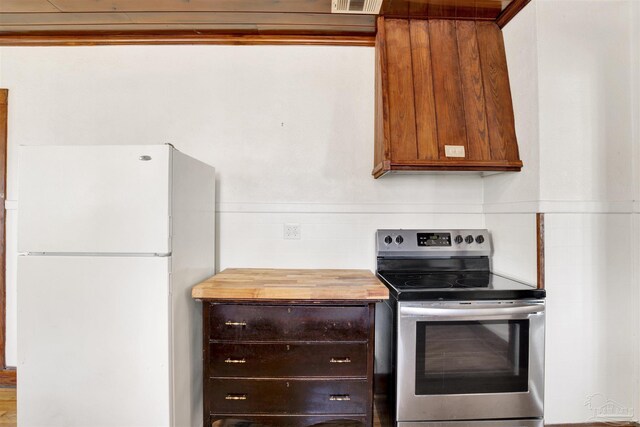 kitchen featuring visible vents, wooden counters, freestanding refrigerator, and stainless steel electric stove