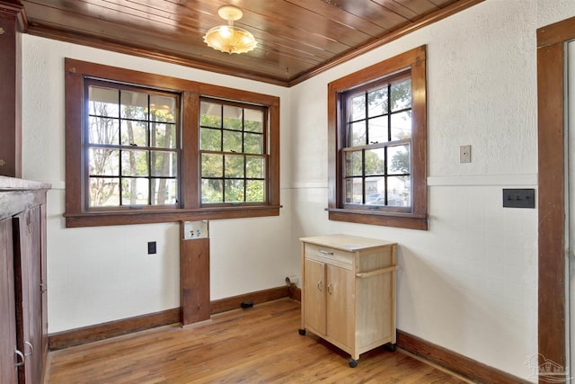 doorway to outside with a textured wall, a wainscoted wall, wood ceiling, crown molding, and light wood-style floors