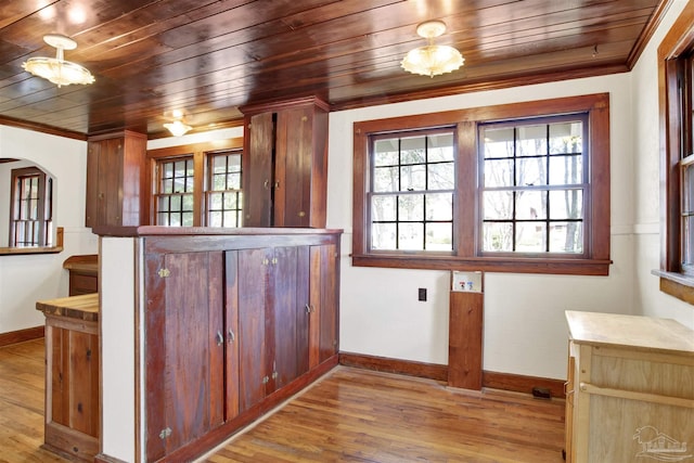 kitchen with arched walkways, wood finished floors, and crown molding