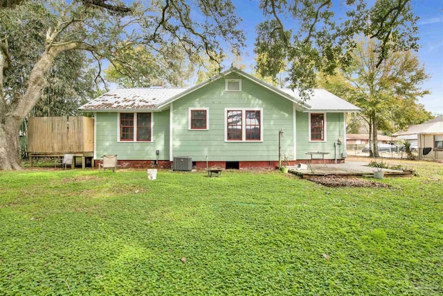 rear view of house with a yard, fence, and central AC unit