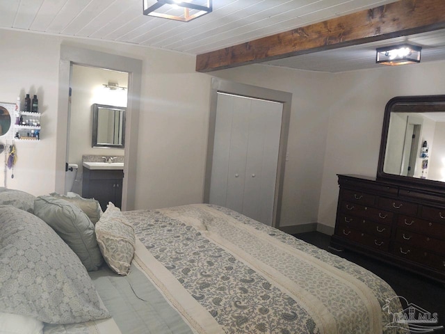 bedroom featuring a closet, wooden ceiling, connected bathroom, and beamed ceiling