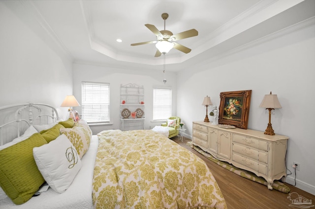 bedroom featuring wood-type flooring, ornamental molding, a tray ceiling, and ceiling fan