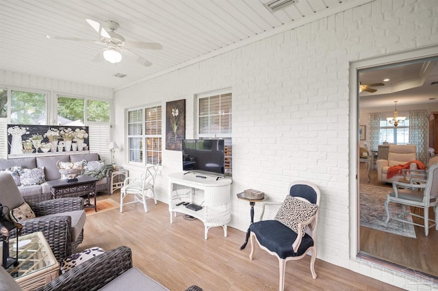 sunroom with ceiling fan with notable chandelier and wood ceiling