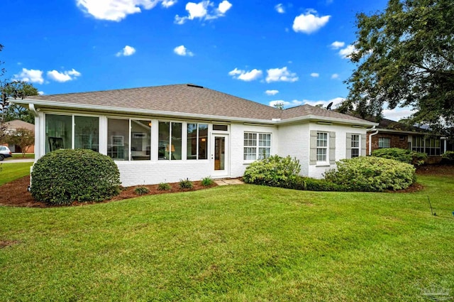 rear view of property featuring a sunroom and a lawn