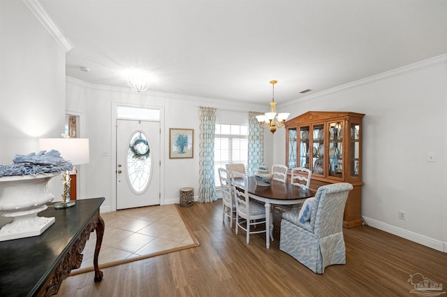 dining room with ornamental molding, hardwood / wood-style floors, and a notable chandelier