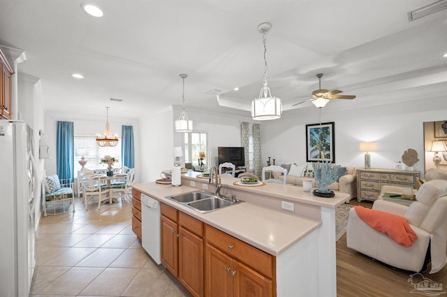 kitchen featuring an island with sink, light tile patterned floors, sink, white appliances, and crown molding