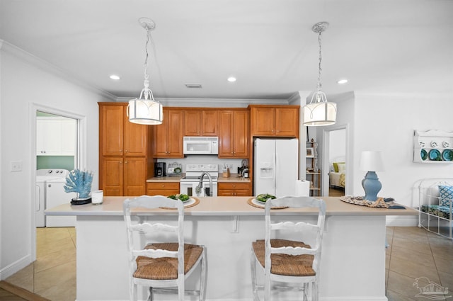 kitchen featuring white appliances, a kitchen bar, washer and dryer, and a large island with sink