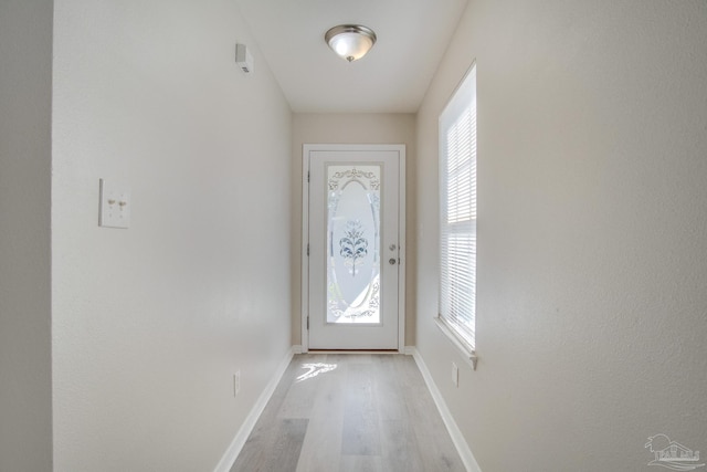 doorway to outside featuring baseboards and light wood finished floors