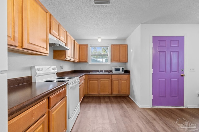 kitchen featuring dark countertops, visible vents, light wood-style flooring, white appliances, and under cabinet range hood