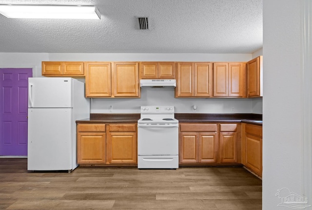 kitchen featuring light wood-style flooring, dark countertops, white appliances, and under cabinet range hood