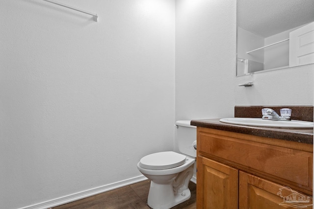 bathroom with baseboards, vanity, toilet, and wood finished floors