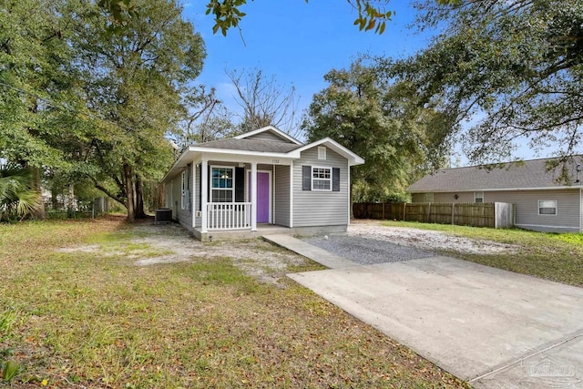 view of front facade featuring a porch, central AC unit, fence, concrete driveway, and a front lawn