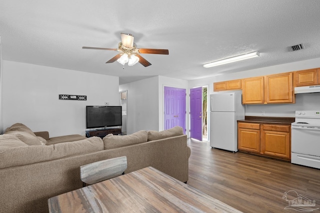 living room with ceiling fan, a textured ceiling, visible vents, and dark wood-style flooring