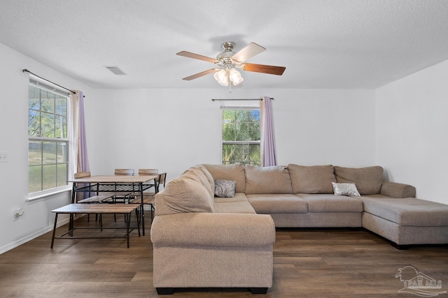 living area featuring a textured ceiling, visible vents, dark wood-style flooring, and a ceiling fan