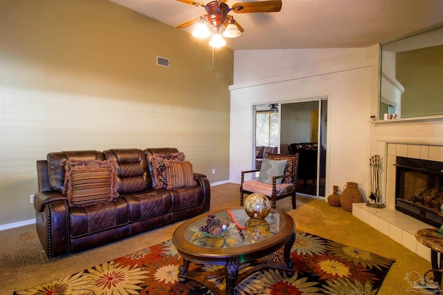 living room with ceiling fan, lofted ceiling, carpet flooring, and a tiled fireplace