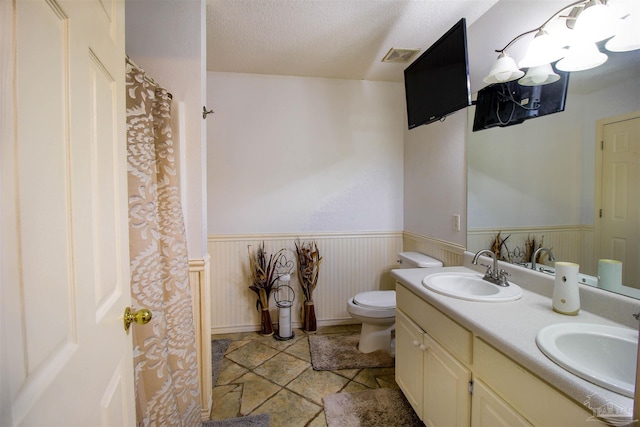 bathroom featuring vanity, toilet, and a textured ceiling