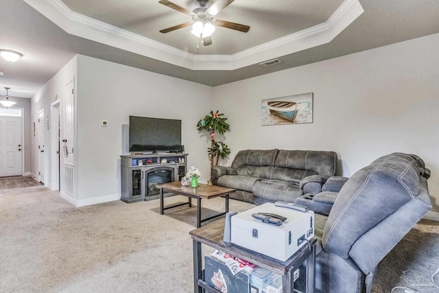 living room featuring a raised ceiling, crown molding, carpet floors, and ceiling fan