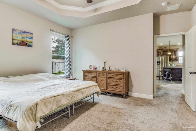 carpeted bedroom with ceiling fan, a raised ceiling, and stainless steel fridge with ice dispenser