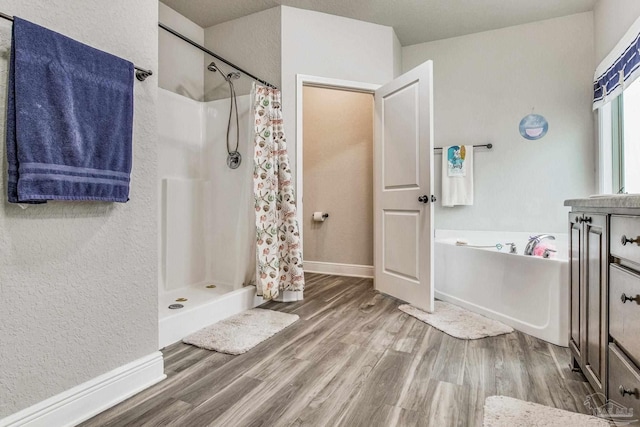 bathroom featuring hardwood / wood-style flooring, vanity, and plus walk in shower