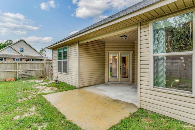 view of exterior entry with a yard and a patio