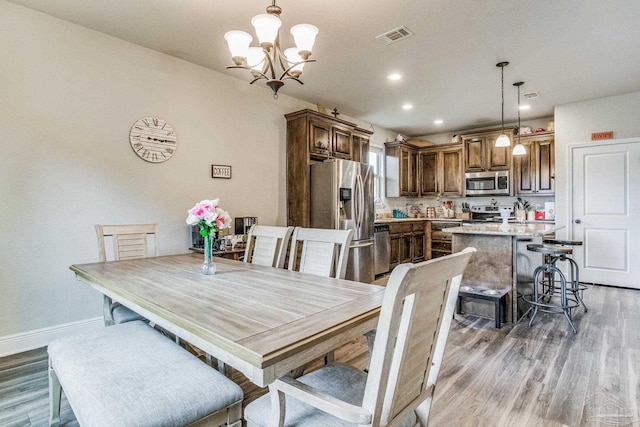 dining space featuring dark wood-type flooring and an inviting chandelier