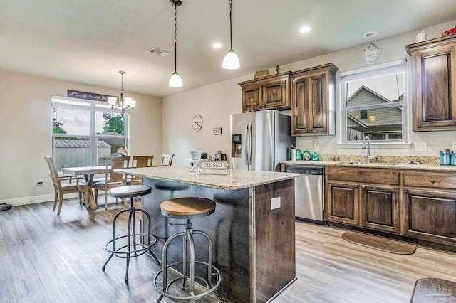 kitchen with a center island, stainless steel appliances, decorative light fixtures, and sink