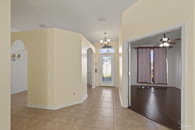 foyer entrance with ceiling fan with notable chandelier and light wood-type flooring