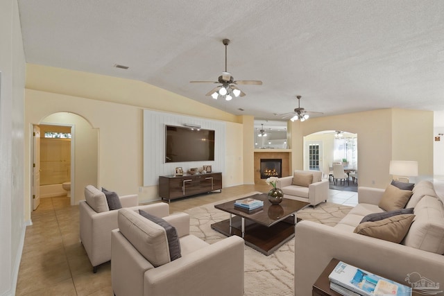 tiled living room with a textured ceiling, ceiling fan, and lofted ceiling