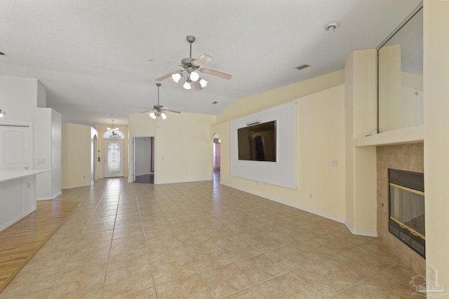 unfurnished living room with ceiling fan, light hardwood / wood-style flooring, a textured ceiling, lofted ceiling, and a tiled fireplace